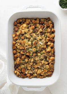 a casserole dish filled with stuffing next to a small bowl of pesto