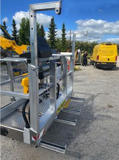 the back end of a trailer with two yellow trucks in the background