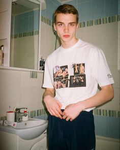 a young man standing in front of a bathroom sink