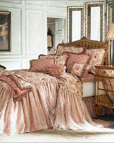 the bed is covered in pink and gold sheets with ruffled trimmings on it