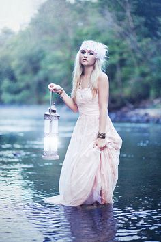 a woman is standing in the water holding a lantern