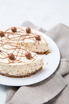 a white plate topped with a cheesecake covered in chocolate