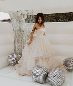 a woman in a white dress standing next to disco balls