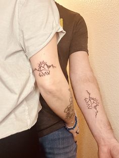 two people with matching tattoos on their arms