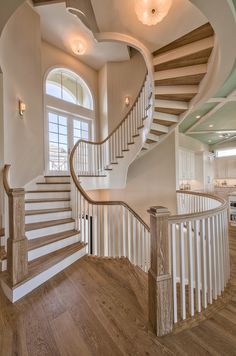 a large staircase in the middle of a room with wooden floors and white railings