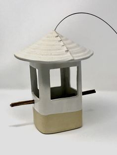 a small white bird house with a wire attached to it