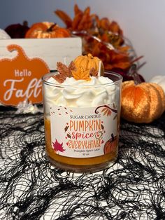 a candle that is sitting on a table with pumpkins and other decorations in the background