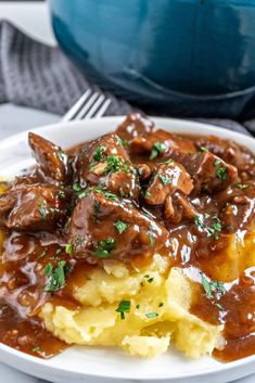 a white plate topped with mashed potatoes covered in gravy