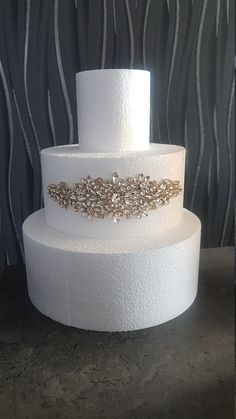 a three tiered white cake with gold accents