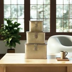 three suitcases sitting on top of a wooden table next to a cup and plant