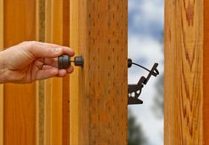 a hand is holding the handle on a wooden fence