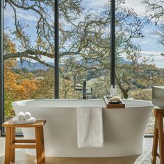 a large bath tub sitting next to two wooden stools in front of a window