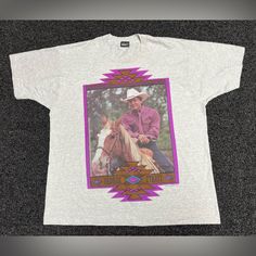 a white t - shirt with an image of a cowboy on the front and purple border