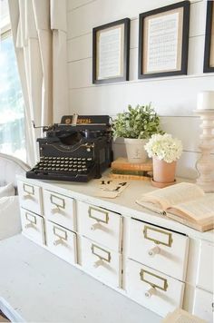 an old fashioned typewriter sitting on top of a white dresser next to a window