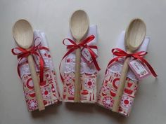 four wooden spoons are wrapped in paper and tied with red ribbon