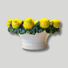 a white vase filled with yellow lemons on top of a table