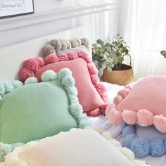 pillows with pom poms on them sitting on a bed