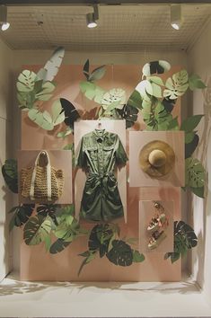 a display case filled with lots of green leaves and hats on top of it's sides