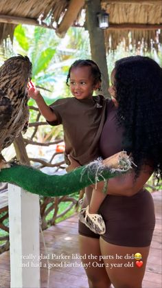 a woman holding an owl on her arm while another person holds it up in front of her