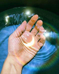 a person's hand is in the water with their reflection on the glass surface