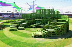 a circular arrangement of wooden pallets in the middle of a grassy area with tables and benches