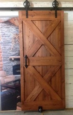 a large wooden door sitting inside of a room next to a brick wall and window