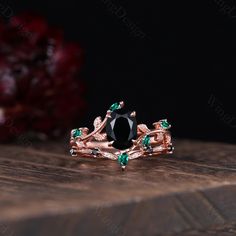 a black diamond and emerald ring on top of a wooden table