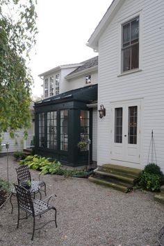 a white house with a black patio and chairs