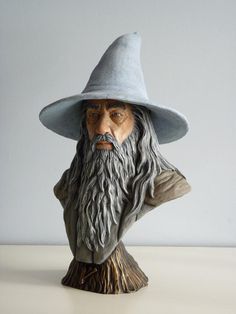 a statue of an old man wearing a gray hat and long beard with his hands behind his head