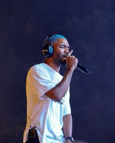 a man with headphones on holding a microphone in front of his face as he sings