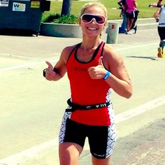 a woman is running on the street with her thumbs up and wearing goggles while giving a thumbs up sign