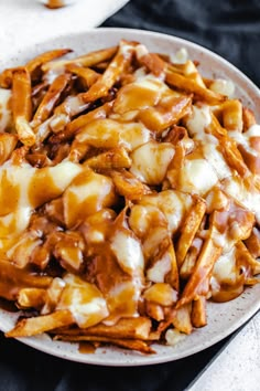 a white plate topped with french fries covered in cheese