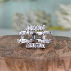 two white gold rings with baguets on top of a wooden table next to flowers