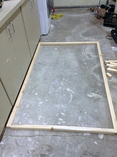 an unfinished frame is sitting in the middle of a kitchen floor that's being worked on