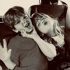 two young children are laughing and having fun on the bus together, one is holding his hand up to his mouth