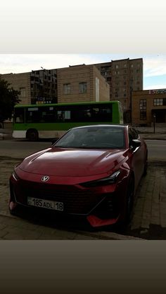 a red sports car parked in front of a green bus