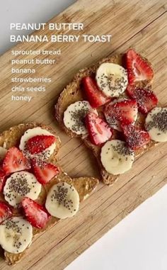 two pieces of toast with sliced strawberries and bananas on top, sitting on a cutting board