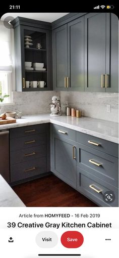 a kitchen with gray cabinets and white counter tops, gold pulls on the handles is shown