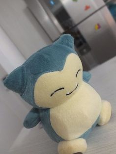 a small stuffed animal sitting on top of a white counter next to a refrigerator freezer