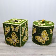 two green and yellow beaded boxes sitting on top of a wooden table next to each other