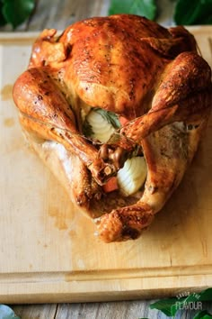 a whole chicken sitting on top of a wooden cutting board