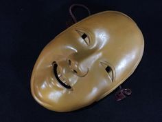 an old mask with a smile on it's face sitting on a black surface