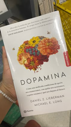 a person holding up a book about dopaminia in front of some bookshelves