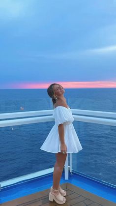 a woman standing on the deck of a cruise ship looking up at the sky and smiling