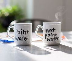 two coffee mugs with the words paint not water written on them sitting next to each other