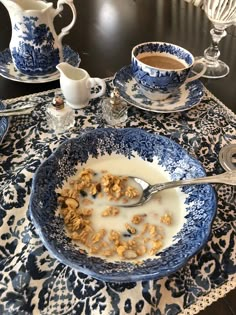 a bowl of cereal and milk on a blue and white tablecloth with silverware