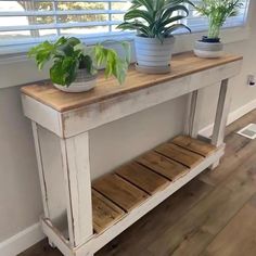 two potted plants sit on top of a wooden shelf in front of a window