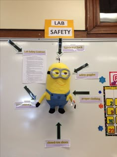 a minion hanging on the side of a white board with magnets attached to it