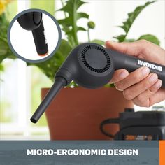 a hand holding a micro - ergonomic design device in front of a potted plant