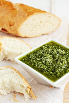 a bowl of pesto next to some bread